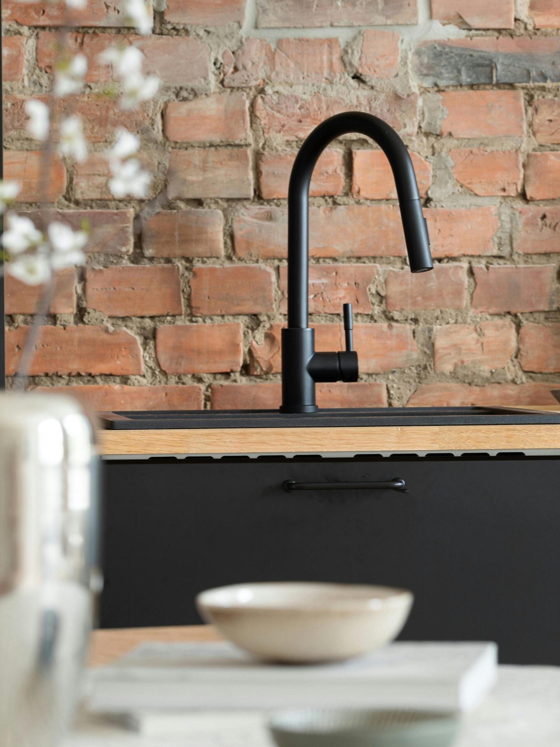 automotive Stylish modern kitchen featuring black faucet, brick wall, and contemporary design elements.