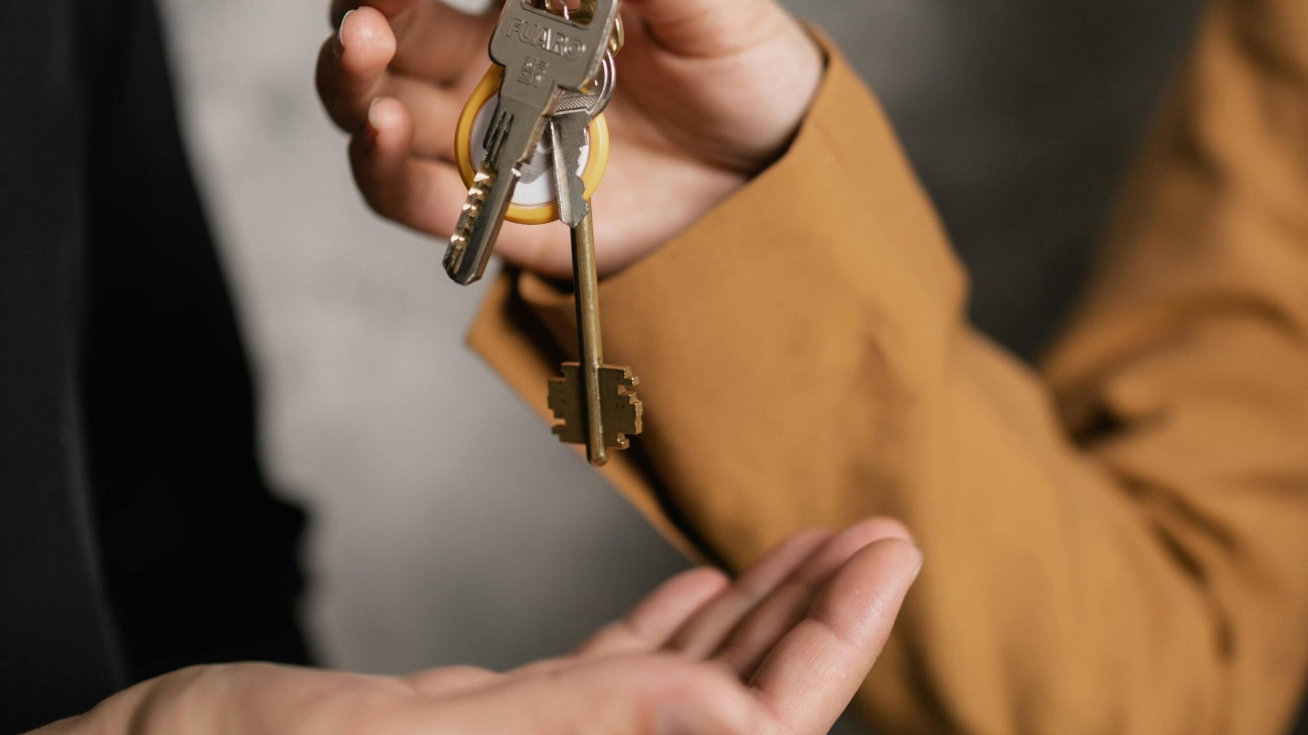 Two adults exchanging house keys, symbolic of property transfer or rental agreement.